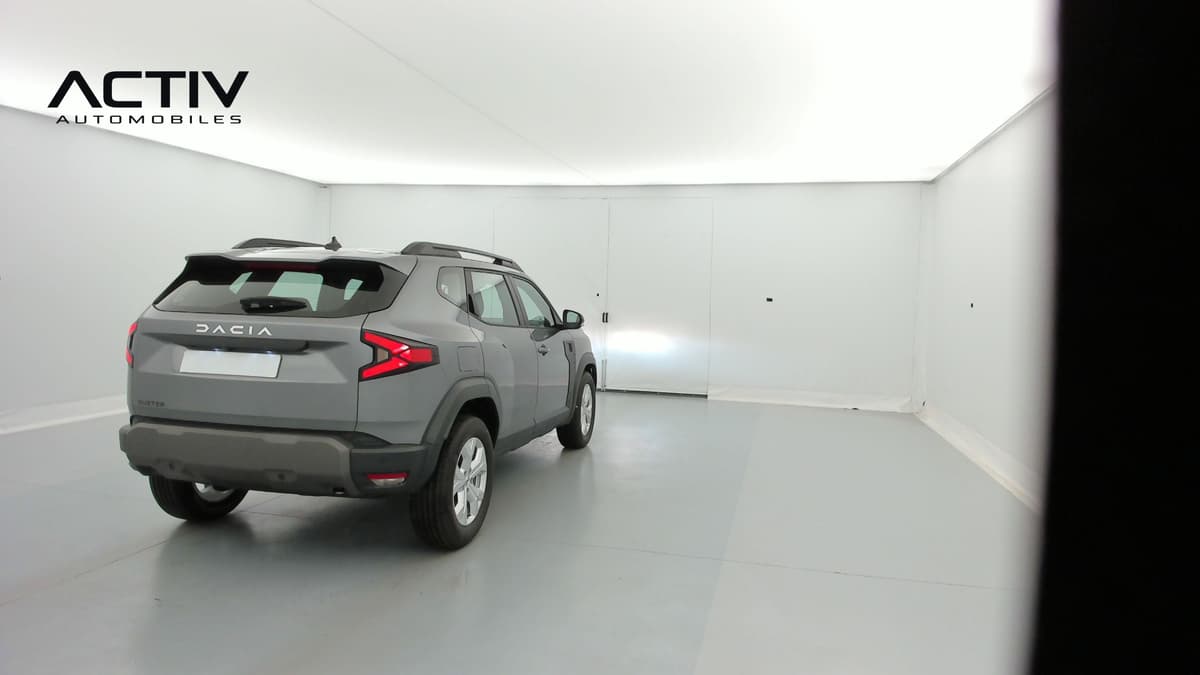Dacia Duster : vue arrière trois quarts droit en gris avec barres de toit et jantes alliage