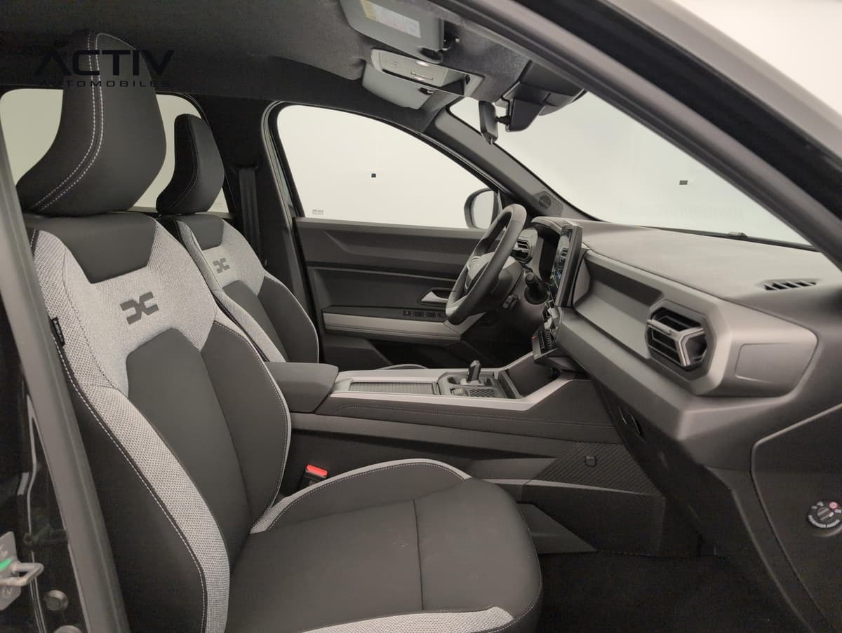 Dacia Bigster Hybrid : siège passager avant en tissu gris et noir, console centrale et volant