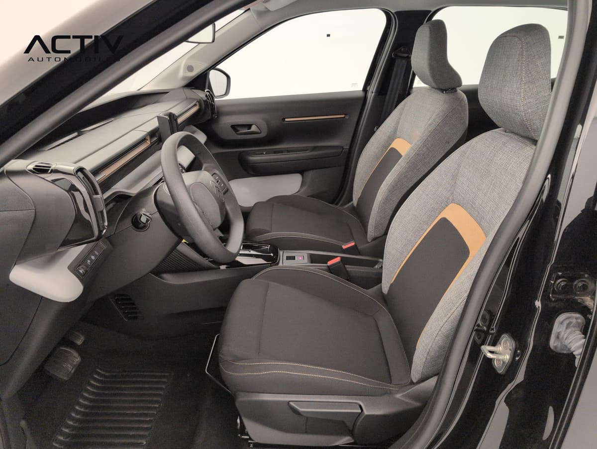 Citroën E-C3 Aircross : sièges avant en tissu gris et noir avec détails orange, vus depuis la portière