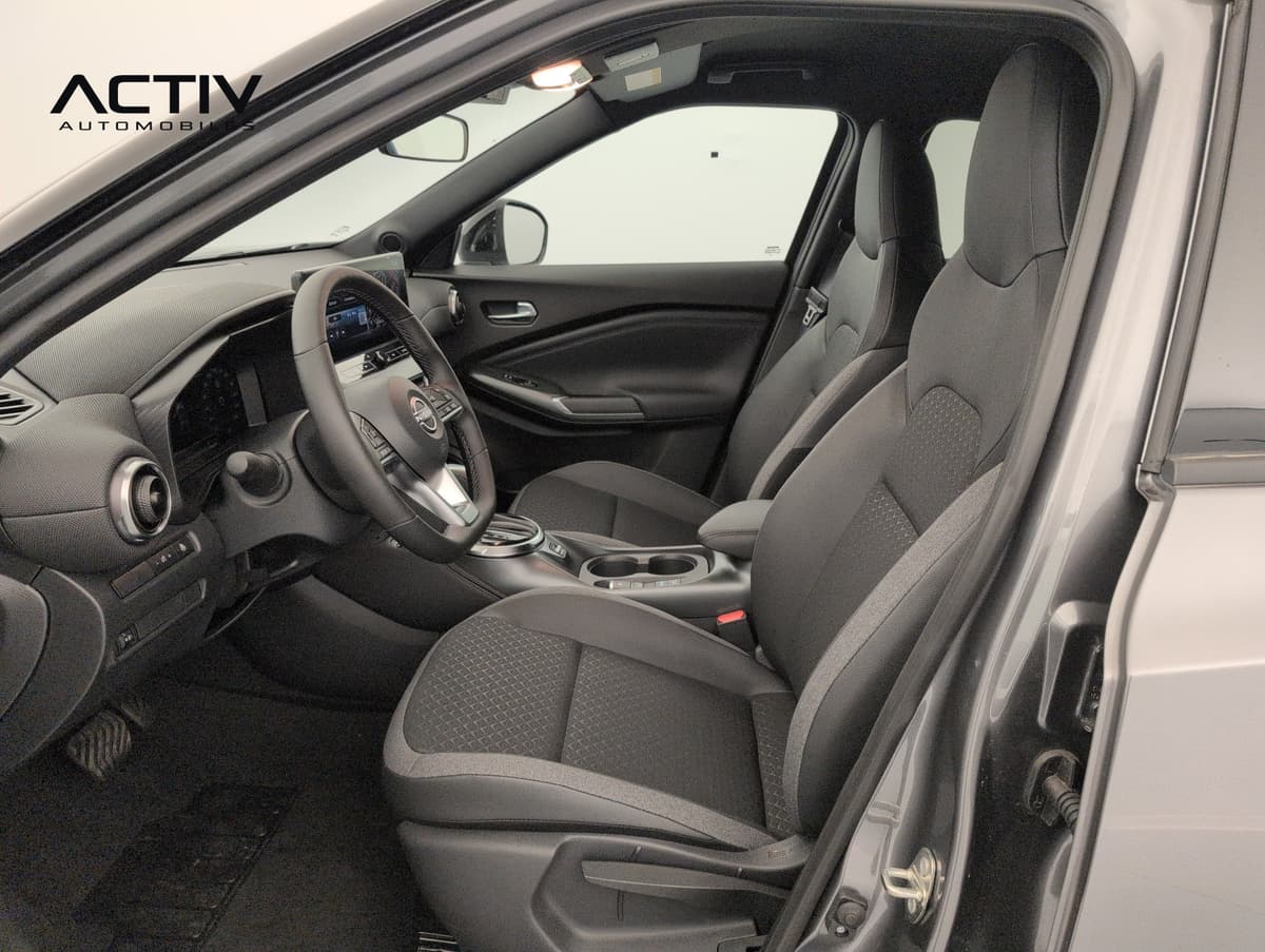 Nissan Juke : habitacle avant côté conducteur vu par la portière ouverte, sièges en tissu noir
