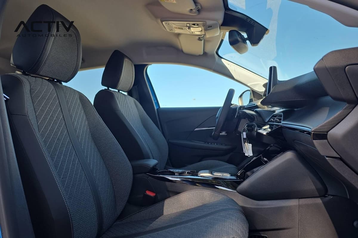 Peugeot 208 : sièges avant en tissu sombre vus côté passager, avec volant et console