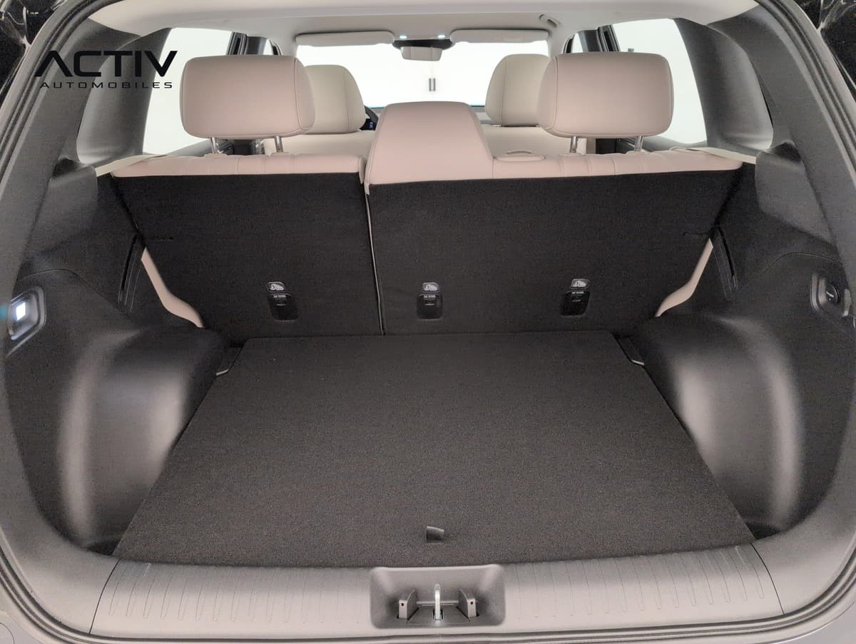 Aion V : coffre ouvert avec plancher plat et banquette arrière beige rabattable