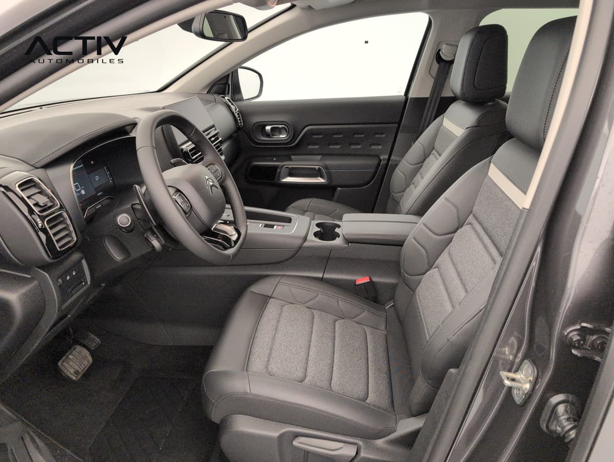 Citroën C5 Aircross : sièges avant en tissu chiné gris et volant, vus par la portière conducteur ouverte
