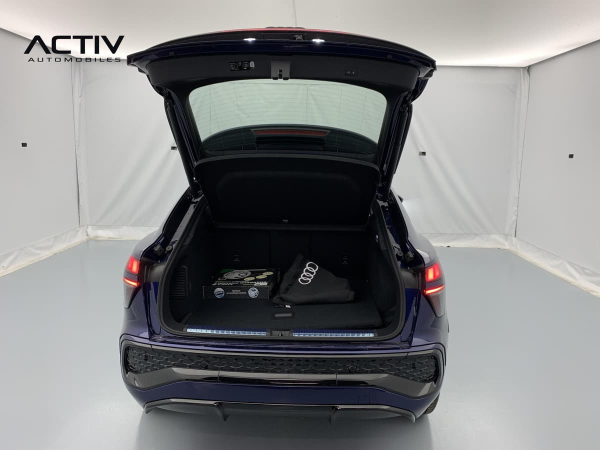 Audi Q3 Sportback Hybride : coffre ouvert avec sac de rangement et kit posés sur le plancher