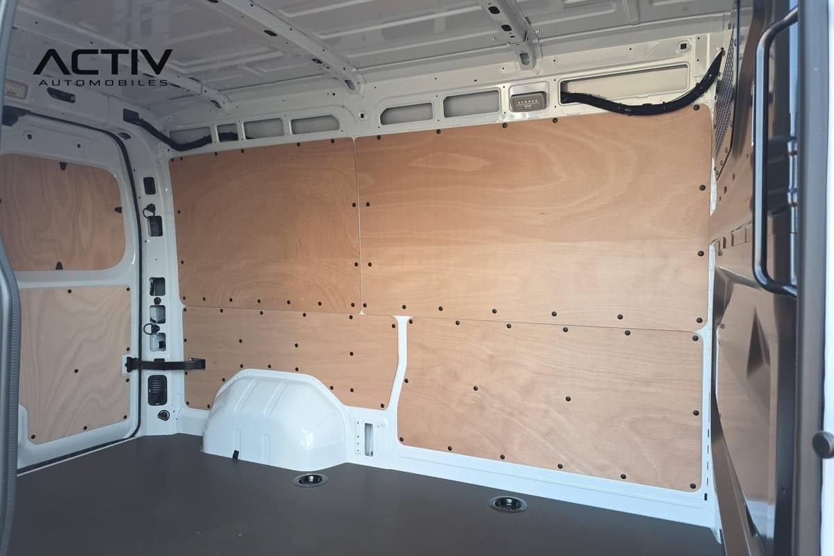 Renault Master Fourgon : zone de chargement habillée de panneaux en bois, plancher gris et points d'ancrage