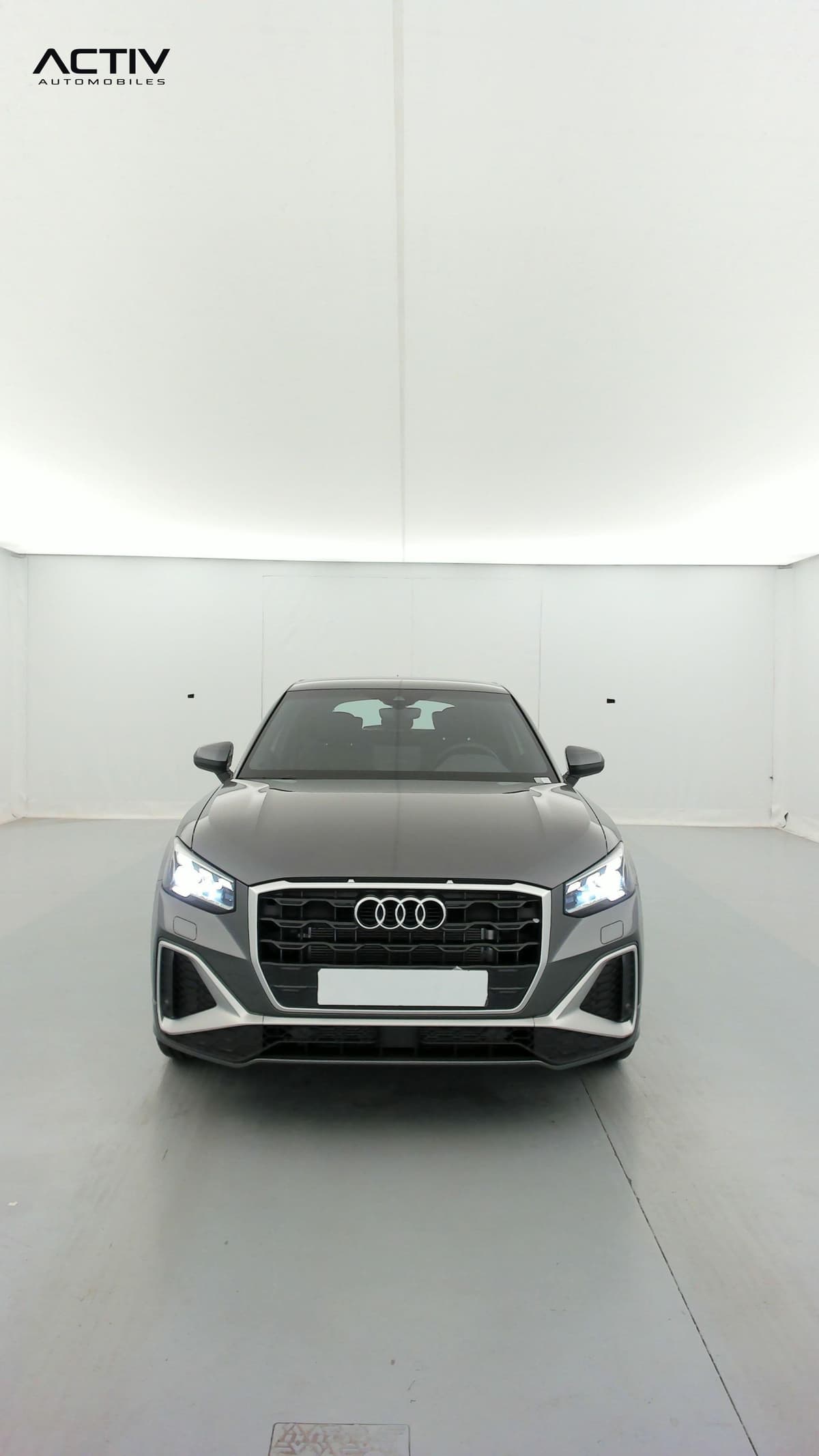 Audi Q2 : face avant avec calandre noire, phares allumés et pare-chocs sport