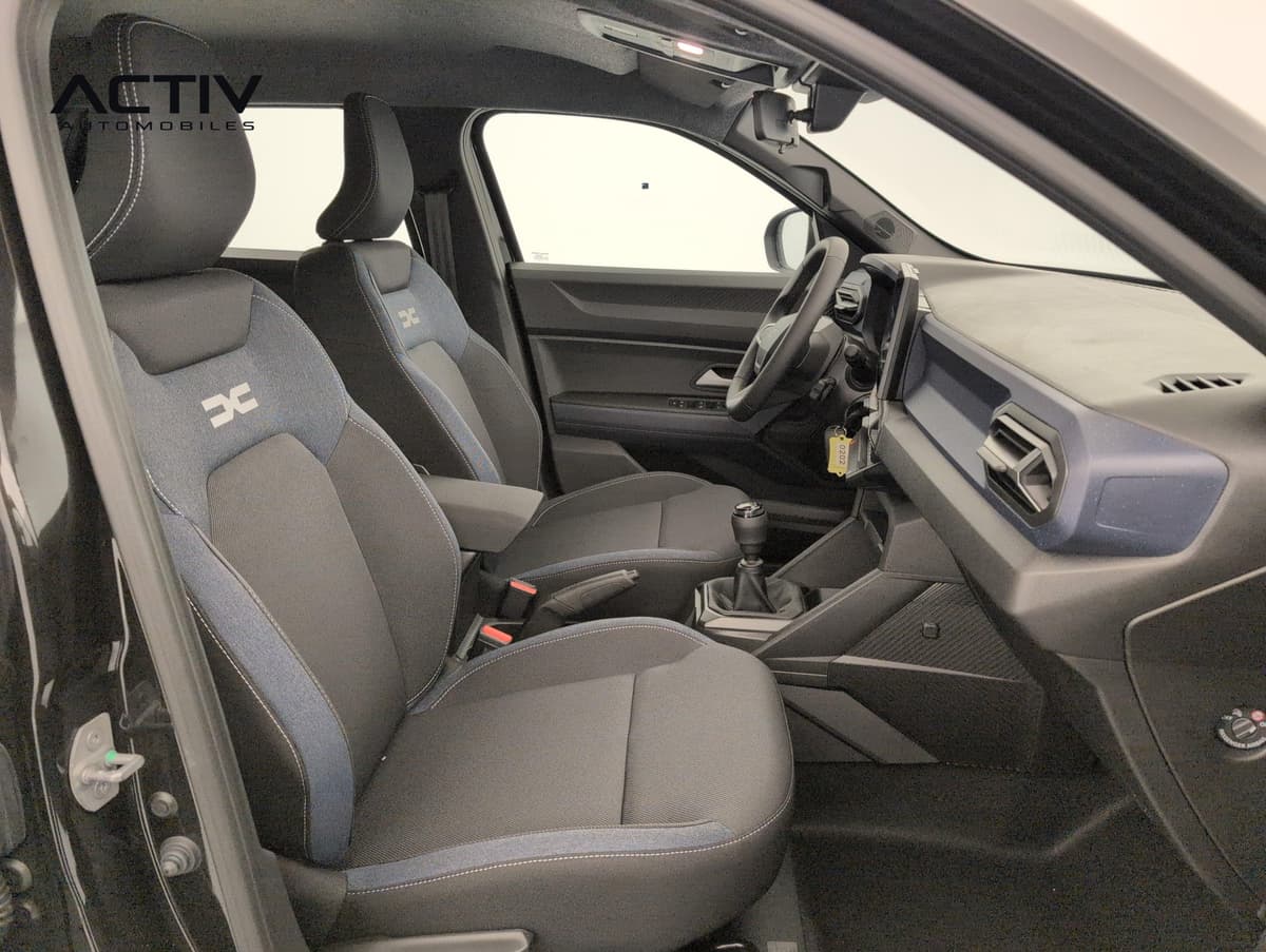 Dacia Duster : sièges avant en tissu denim bleu et noir, vus depuis la portière passager