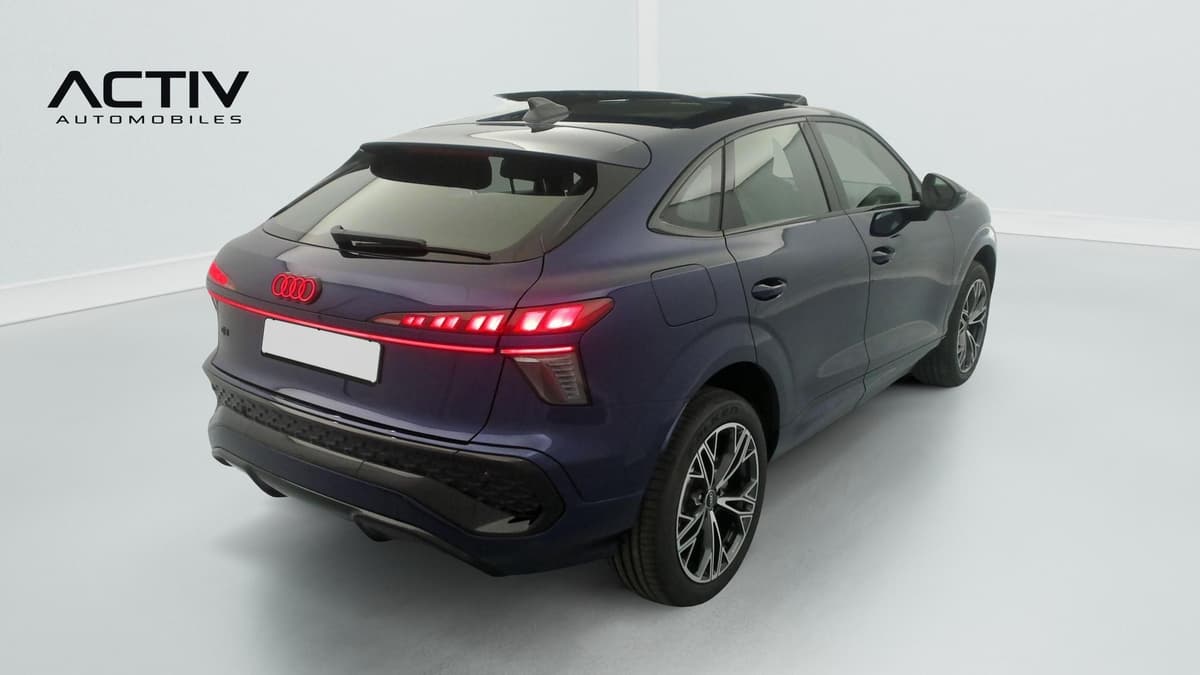 Audi Q3 Sportback Hybride : vue arrière trois quarts droit, bleu foncé, feux allumés, jantes bicolores
