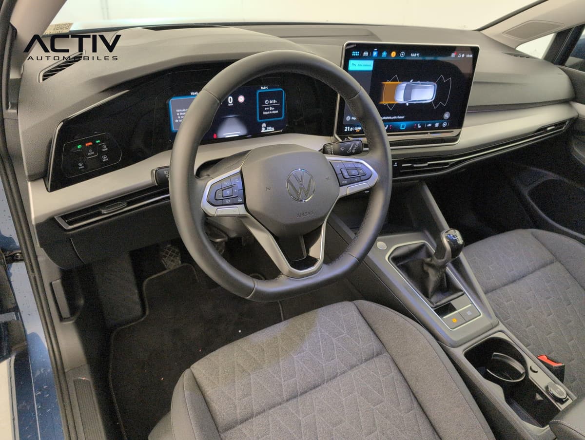 Volkswagen Golf 8 : habitacle avant côté conducteur avec volant, écran tactile et levier manuel