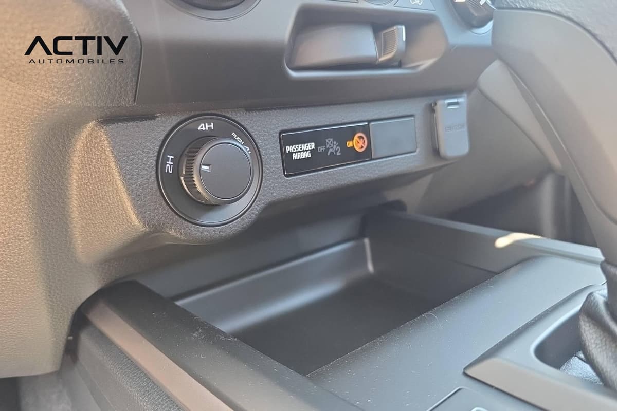 Isuzu D-MAX : molette de sélection 2H/4H et témoin d'airbag passager près d'un bac de rangement