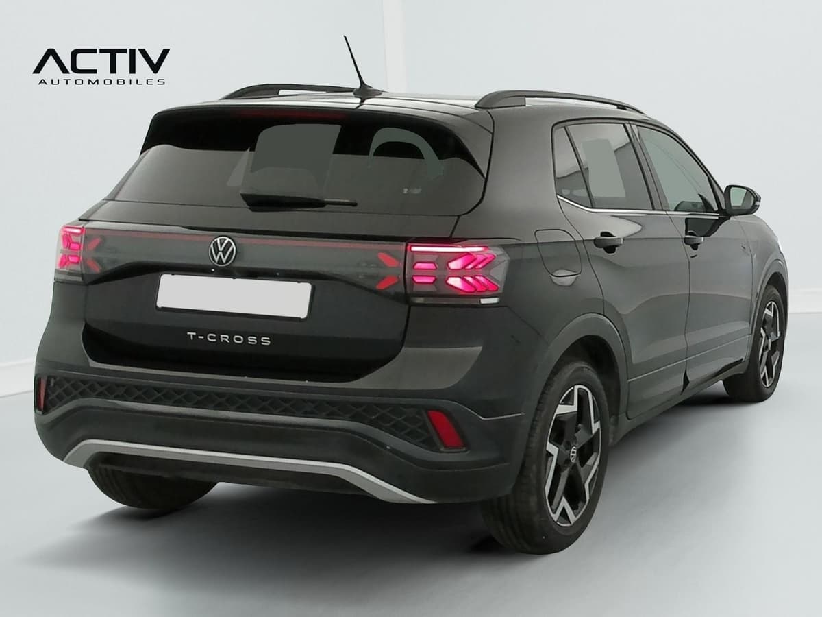 Volkswagen T-cross : arrière trois quarts droit avec feux allumés, jantes bicolores et rampes de pavillon noires