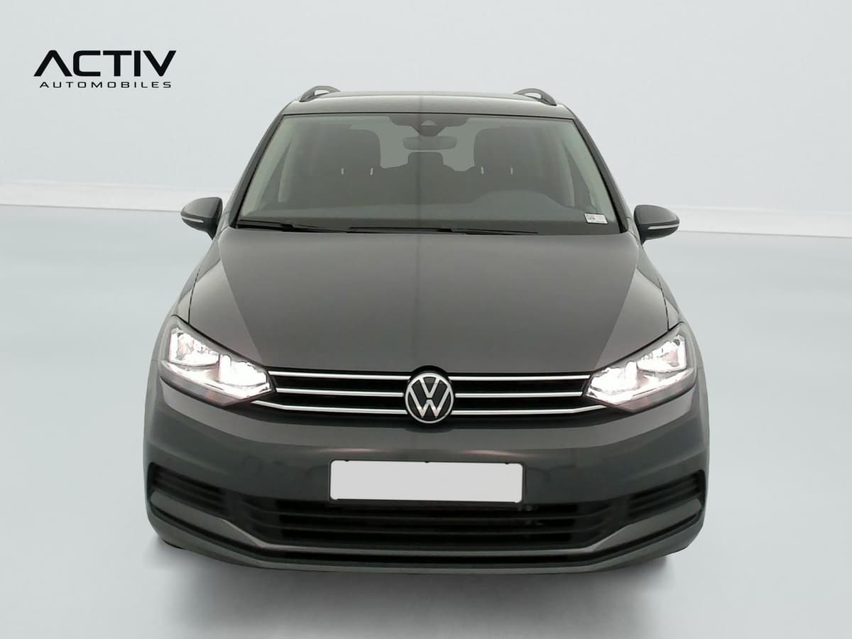 Volkswagen Touran : face avant grise avec calandre chromée, phares allumés et rétroviseurs