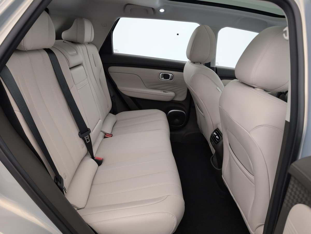 Aion UT : banquette arrière beige vue par la portière ouverte, avec ceintures noires