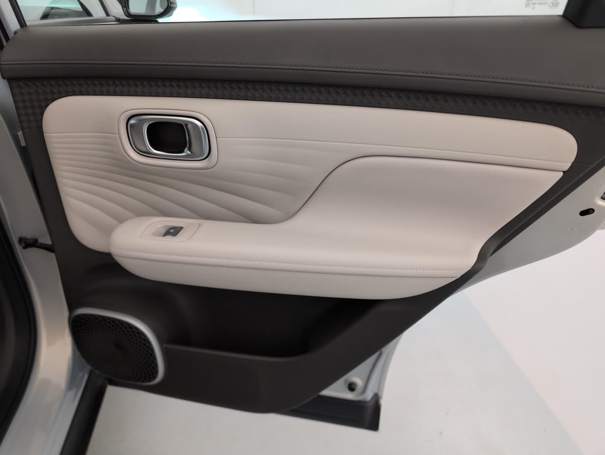 Aion UT : panneau de porte arrière beige avec accoudoir, commande de vitre et haut-parleur